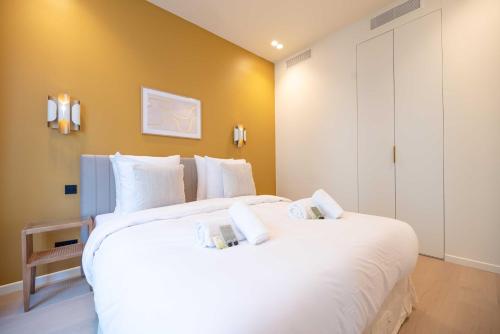 - une chambre avec un grand lit blanc et des oreillers blancs dans l'établissement Elegant Apt with AC - 2BR-6P -Palais Garnier, à Paris