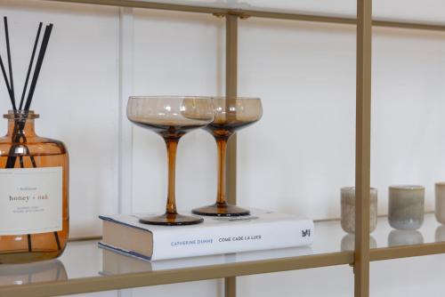 two wine glasses on a shelf with books at President Boutique Apartments #8 by Goodnite cz in Brno