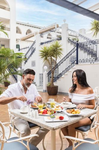 un hombre y una mujer sentados en una mesa desayunando en Mac Puerto Marina Benalmádena, en Benalmádena