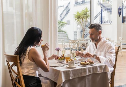 Un hombre y una mujer sentados en una mesa comiendo comida en Mac Puerto Marina Benalmádena, en Benalmádena
