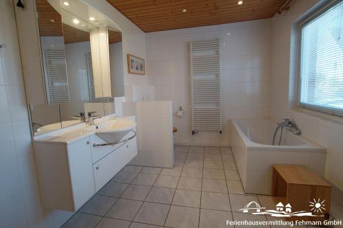 a white bathroom with a tub and a sink and a tub and a bath tub at 14 Ferienwohnung Inselparadies in Petersdorf auf Fehmarn