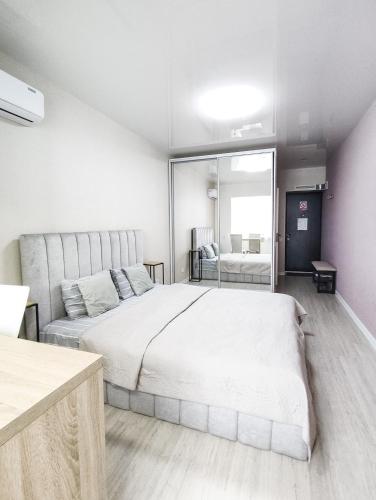 a bedroom with a large white bed and a mirror at Радужная студия Вокзал Харьков-Пассажирский in Kharkiv