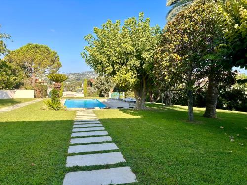 un jardin avec un chemin en pierre dans la pelouse dans l'établissement Villa El Sol Antibes, à Juan-les-Pins