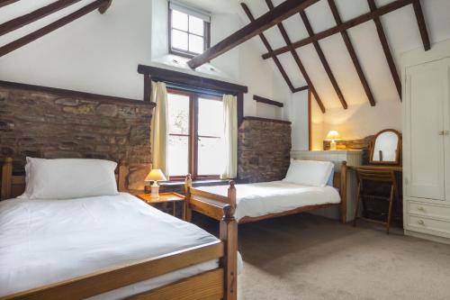 a bedroom with two beds and a desk and a window at The Granary nr Huntsham in Tiverton