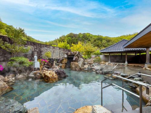 a swimming pool with a waterfall and a stone wall at Mercure Kochi Tosa Resort & Spa in Geisei
