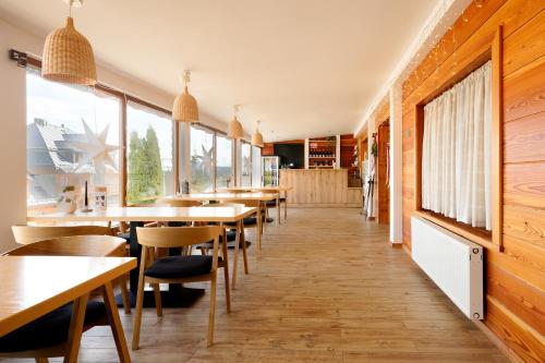 a restaurant with wooden floors and tables and windows at Willa Sasanka in Duszniki Zdrój
