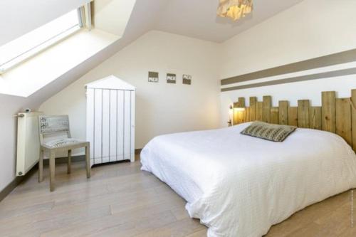 une chambre avec un grand lit blanc et une chaise dans l'établissement Maison Moderne pour 8 personnes Côte sauvage, à Quiberon