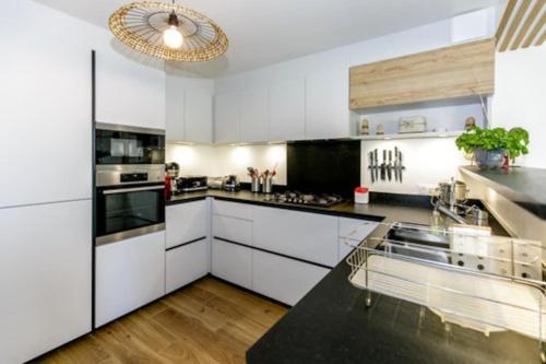 une cuisine avec des armoires blanches et un comptoir noir dans l'établissement Maison Moderne pour 8 personnes Côte sauvage, à Quiberon