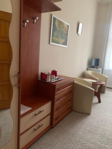 a room with a dresser and a chair in a room at Szent István Wellness Panzió in Makó