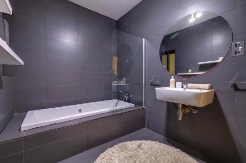 a bathroom with a tub and a sink and a mirror at Modern 2BR Sliema Apartment in Sliema