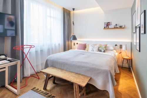 a bedroom with a bed and a bench next to a window at MOSAIC HOUSE Design Hotel in Prague