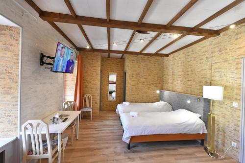 a room with two beds and a table and chairs at Les Portes du Cantal in Massiac