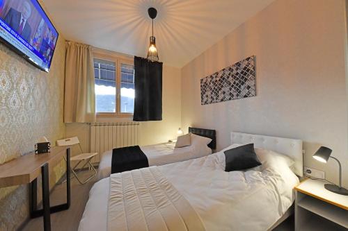 a hotel room with two beds and a television at Les Portes du Cantal in Massiac