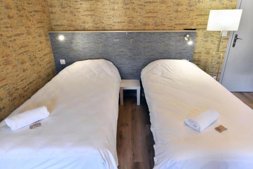 two beds in a room next to a table at Les Portes du Cantal in Massiac