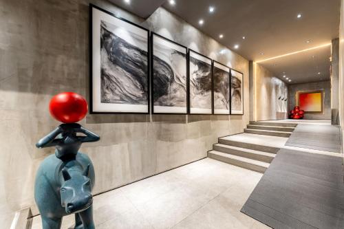 a statue of a woman with a red hat looking at paintings at HeSu Hidden Art Hotel & Suites - Near Bell Tower & Ideal Location-Spacious rooms featuring King or Double Queen beds -Exclusive Two&Three-Bedroom Suites with Expansive Living Rooms for Group Gathering-Kitty Cuddles & Coffee Gift -Seamless Journey Planning in Xi'an