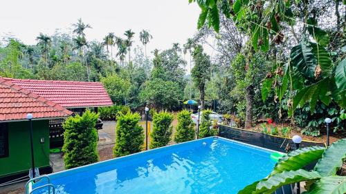 a swimming pool in front of a house with trees at Golden pearl private villa with pool in Vythiri