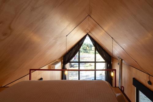 a bed in a room with a triangular window at Refugios Pura vida in La Paloma