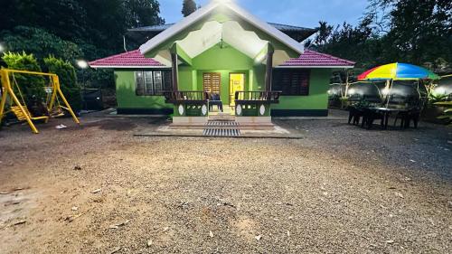 a small green house with a playground and umbrella at Golden pearl private villa with pool in Vythiri