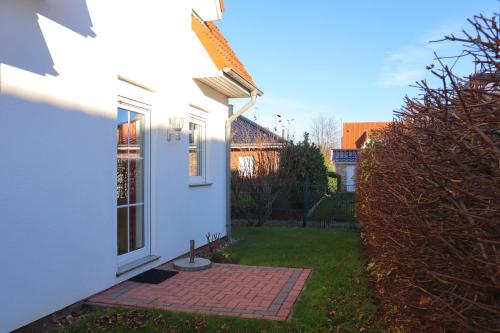 a white house with a yard with a brick walkway at Villa am Meer - Casa Mia in Dorum Neufeld