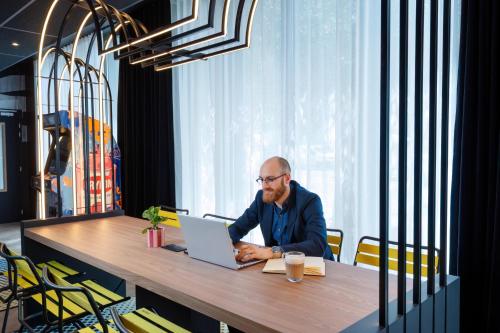 a man sitting at a table with a laptop at Aparthotel Adagio Access Rouen Centre Cathédrale in Rouen