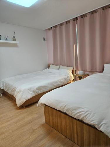 due letti in una stanza con lenzuola bianche di Hongdae ssuny house a Seul