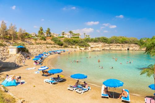 a group of people on a beach with blue umbrellas at Villa Koula in Paralimni