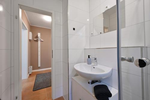 Un baño blanco con lavabo y espejo. en SANO - Bei Holger in Hagen - Ruhige Lage - Stylisch - Waschmaschine - Platz zum Arbeiten, en Hagen