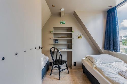 a bedroom with a bed and a chair in a attic at Luxury private farmhouse cottage near Amsterdam plus home cinema in Ilpendam
