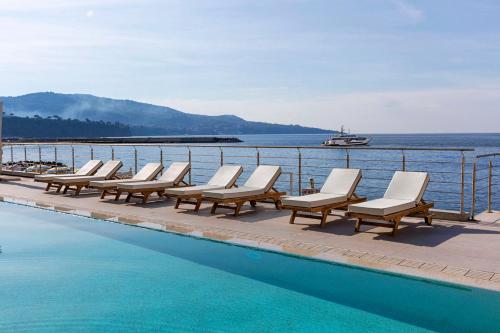 a row of lounge chairs next to a swimming pool at Alimuri Bay Resort in Meta