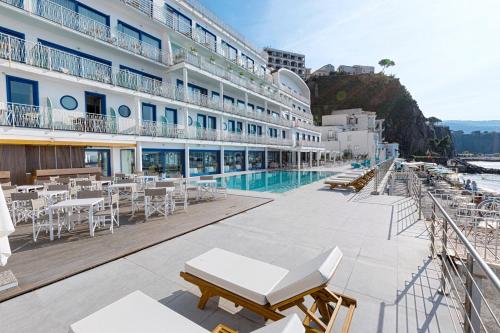 a large hotel with a pool and tables and chairs at Alimuri Bay Resort in Meta
