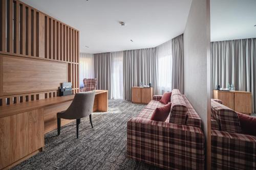 a hotel room with a couch and a desk at Hotel Meta Resort & Vine SPA in Szczyrk