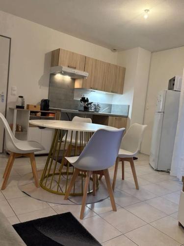 a kitchen with a table and chairs and a refrigerator at Appartement au calme proche du PAL in Digoin