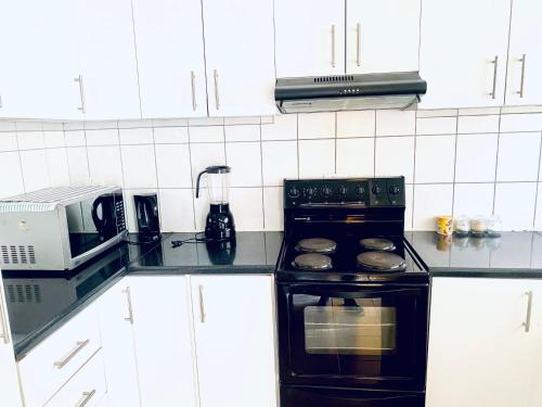 a kitchen with a black stove and a microwave at Apartment at Jenner in Windhoek