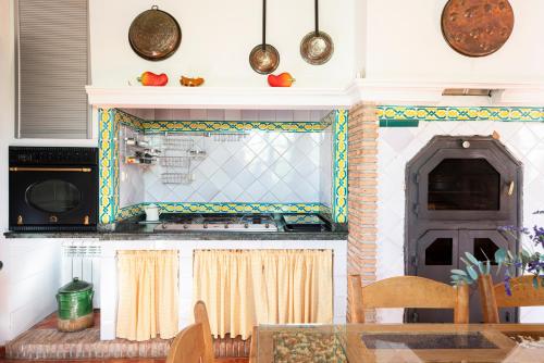 a kitchen with a table and a stove and a microwave at Casa rural Buenos Días con chimenea, calefacción y barbacoa in Padul
