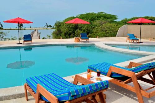 a swimming pool with chairs and umbrellas at King baobab lodge in Diakhanor