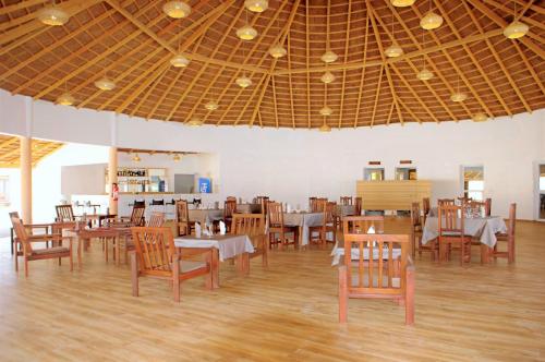 a dining room with tables and chairs and a ceiling at King baobab lodge in Diakhanor