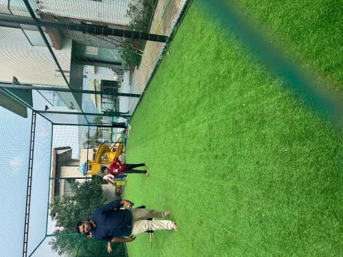 a group of people standing next to a green field at Royal Twin Lonavla - 12BHK Luxury Villa with Turf in Lonavala