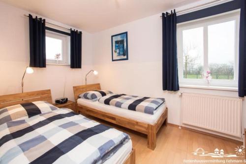 two beds in a room with two windows at 18 Ferienwohnung im Fritz-Bleyl-Weg 16a EG in Burg auf Fehmarn