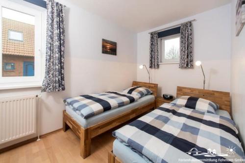 two beds in a room with two windows at 19 Ferienwohnung im Fritz-Bleyl-Weg 16b EG in Burg auf Fehmarn