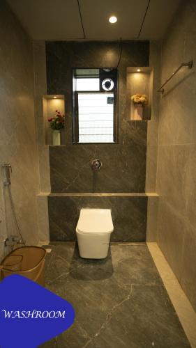 a bathroom with a toilet and a window at Royal Twin Lonavla - 12BHK Luxury Villa with Turf in Lonavala