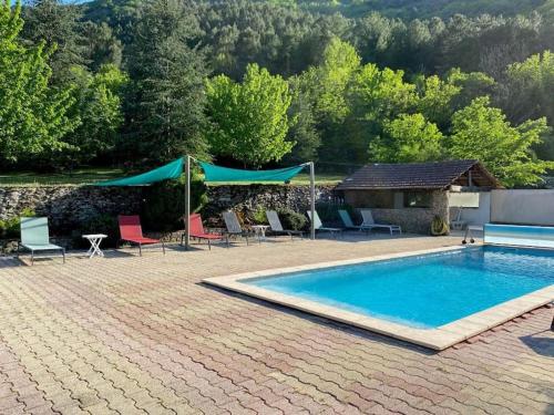 une piscine avec chaises et parasols devant une maison dans l'établissement Gîte de 6 ou 8 personnes le Châtaignier, à Gravières