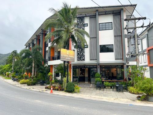 a building with a palm tree in front of a street at PP GRAND KAMALA HOTEL-SHA Extra Plus in Kamala Beach