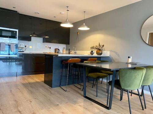 a kitchen with a table and some green chairs at Luxury apartment close to Theatre, Barbican & Hoe 2 kings or 4 single beds secure covered parking in Plymouth