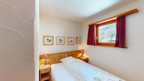 a small bedroom with a bed and a window at Apartment Ambretta OG in Champfer