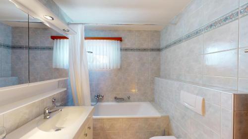 a bathroom with a tub and a toilet and a sink at Apartment Ambretta OG in Champfer