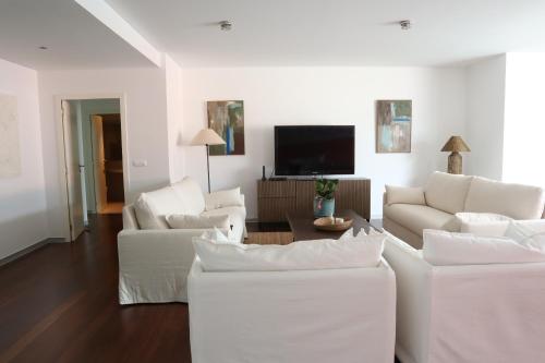 a living room with white furniture and a flat screen tv at Heart of Funchal 4 BD Apartment - Casa d Alma in Funchal