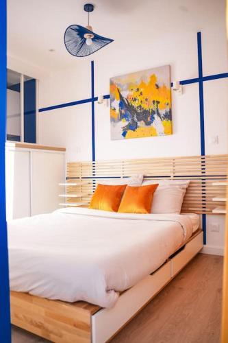 une chambre avec un grand lit blanc avec des oreillers orange dans l'établissement Studio Majorelle, à Sotteville-lès-Rouen