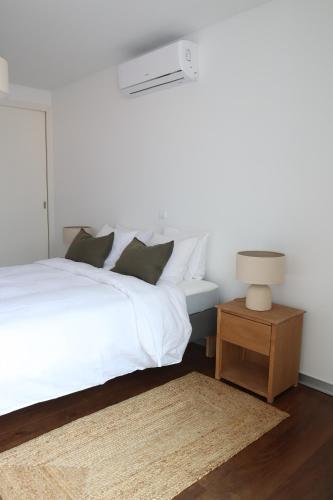 a bedroom with a white bed and a table with a lamp at Heart of Funchal 4 BD Apartment - Casa d Alma in Funchal