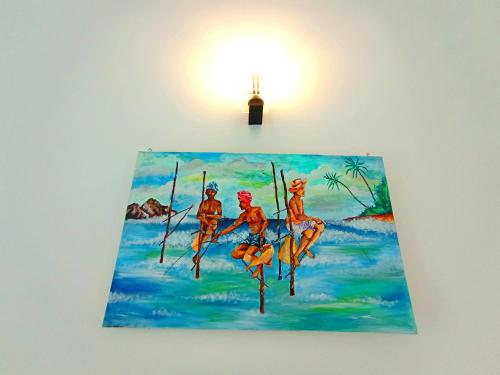 a painting of three men on sticks in the water at Would Villa Mirissa in Mirissa