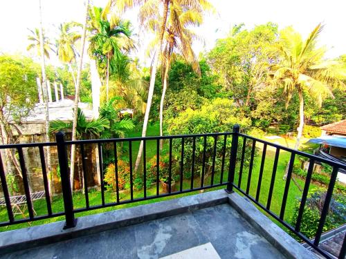a balcony with a black railing and palm trees at Would Villa Mirissa in Mirissa